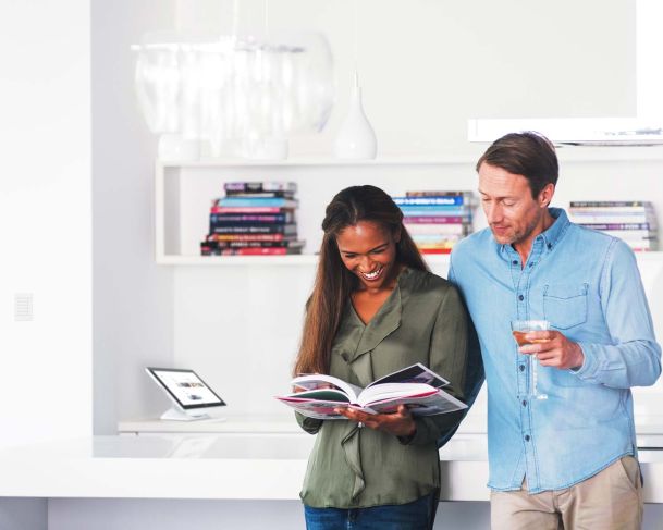 couple looking at book in front of crestron touch panel