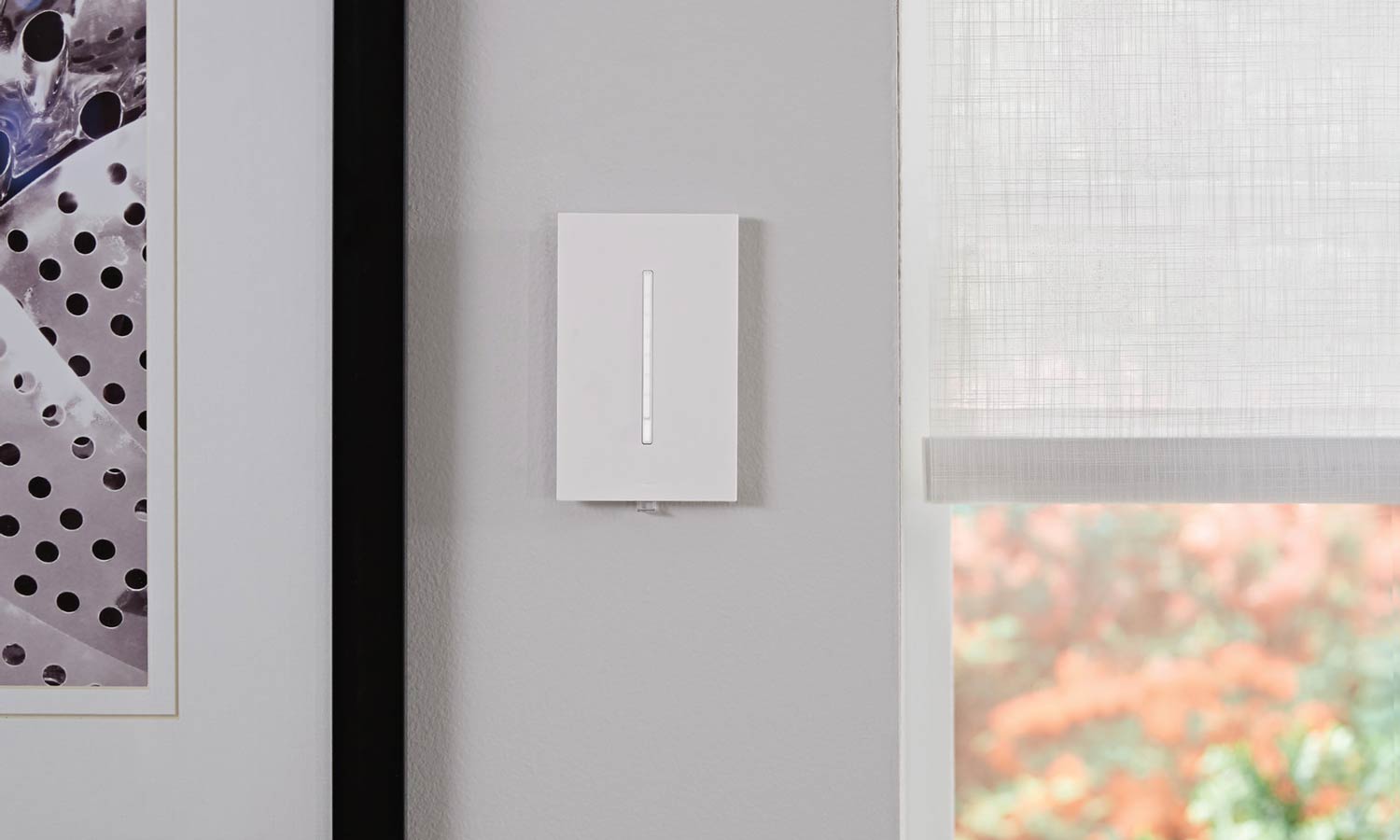 Modern wall‑mounted smart dimmer switch in a minimalist interior setting.