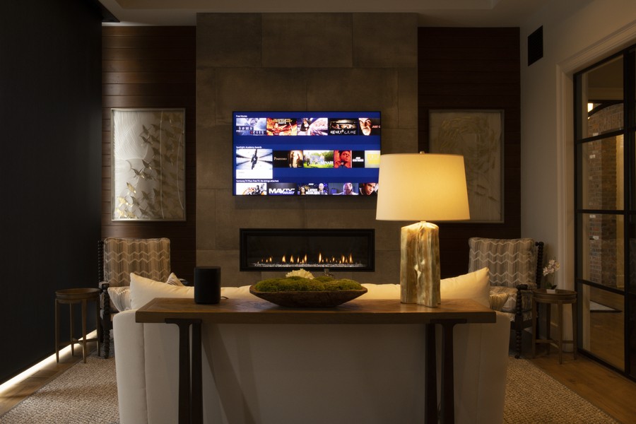 Dimly lit living room with a fireplace and wall-mounted TV displaying content.