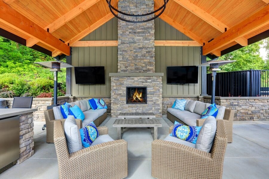 An outdoor AV system and setup on a patio featuring two screens and a fireplace in the center.